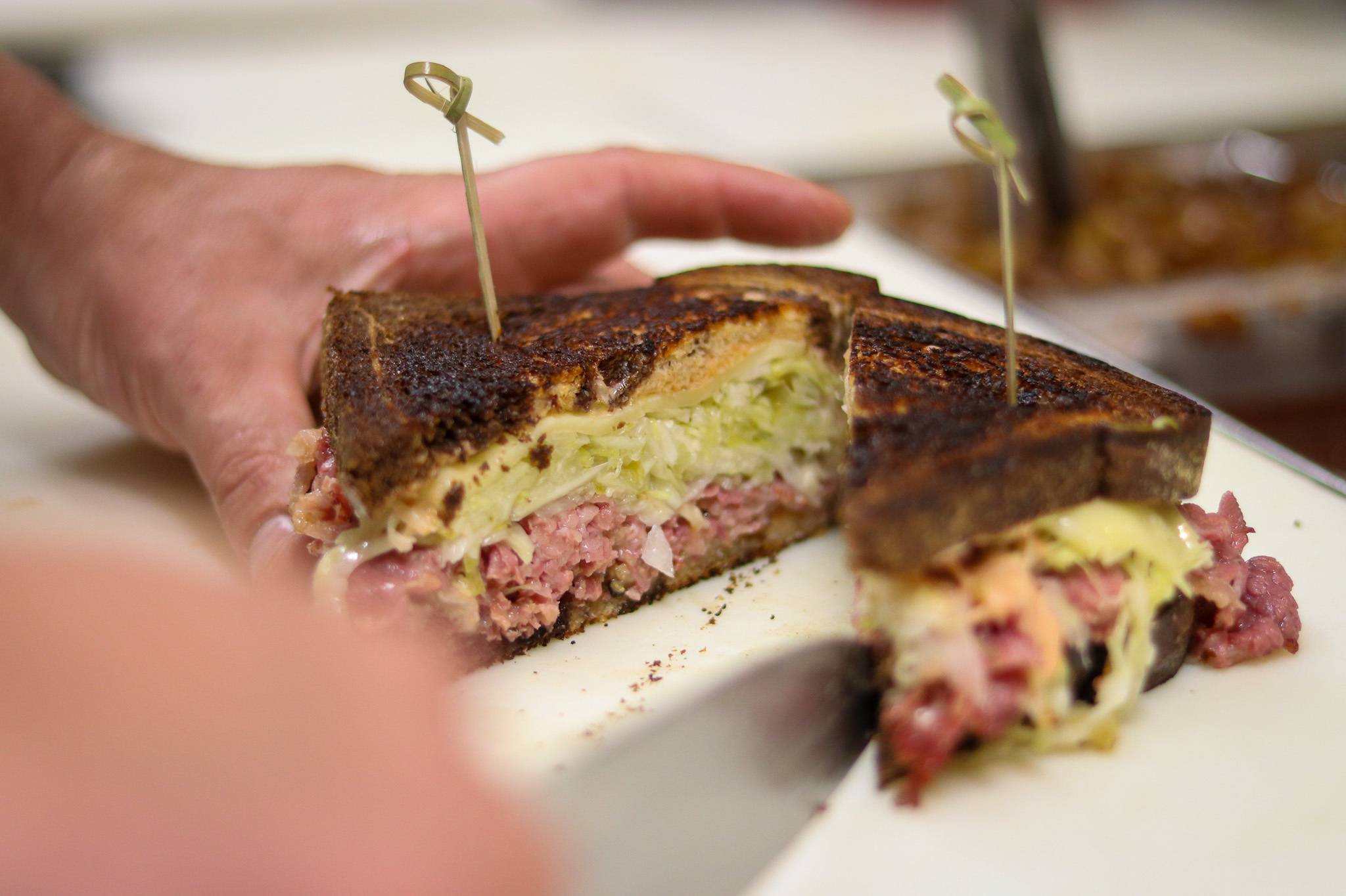 Chef cutting a reuben sandwich in half